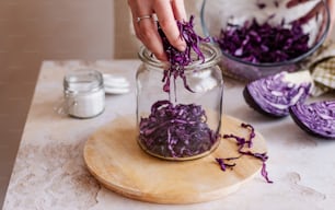 a person putting purple cabbage in a jar