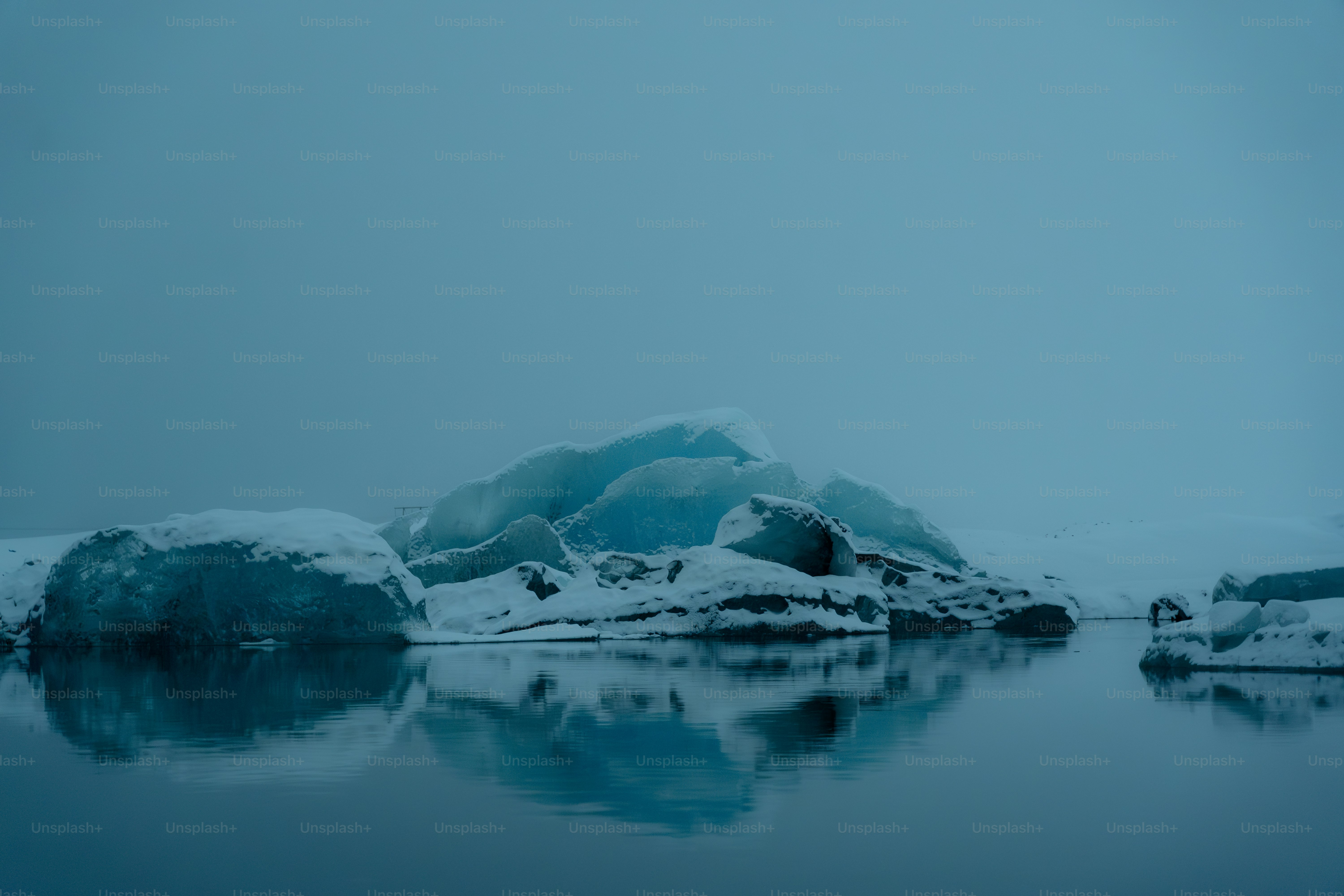 a body of water surrounded by snow covered rocks