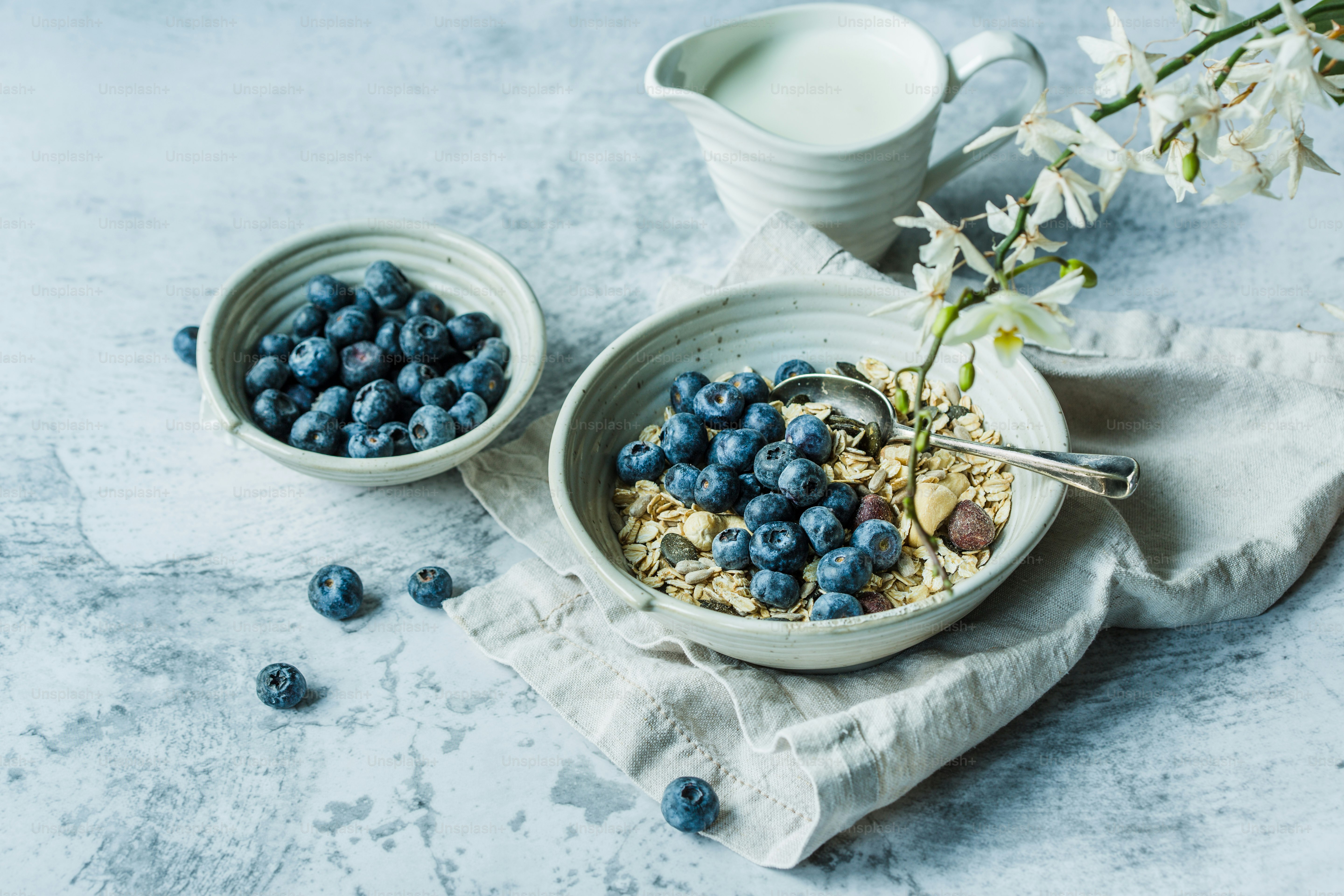 a bowl of oatmeal with blueberries and a cup of milk