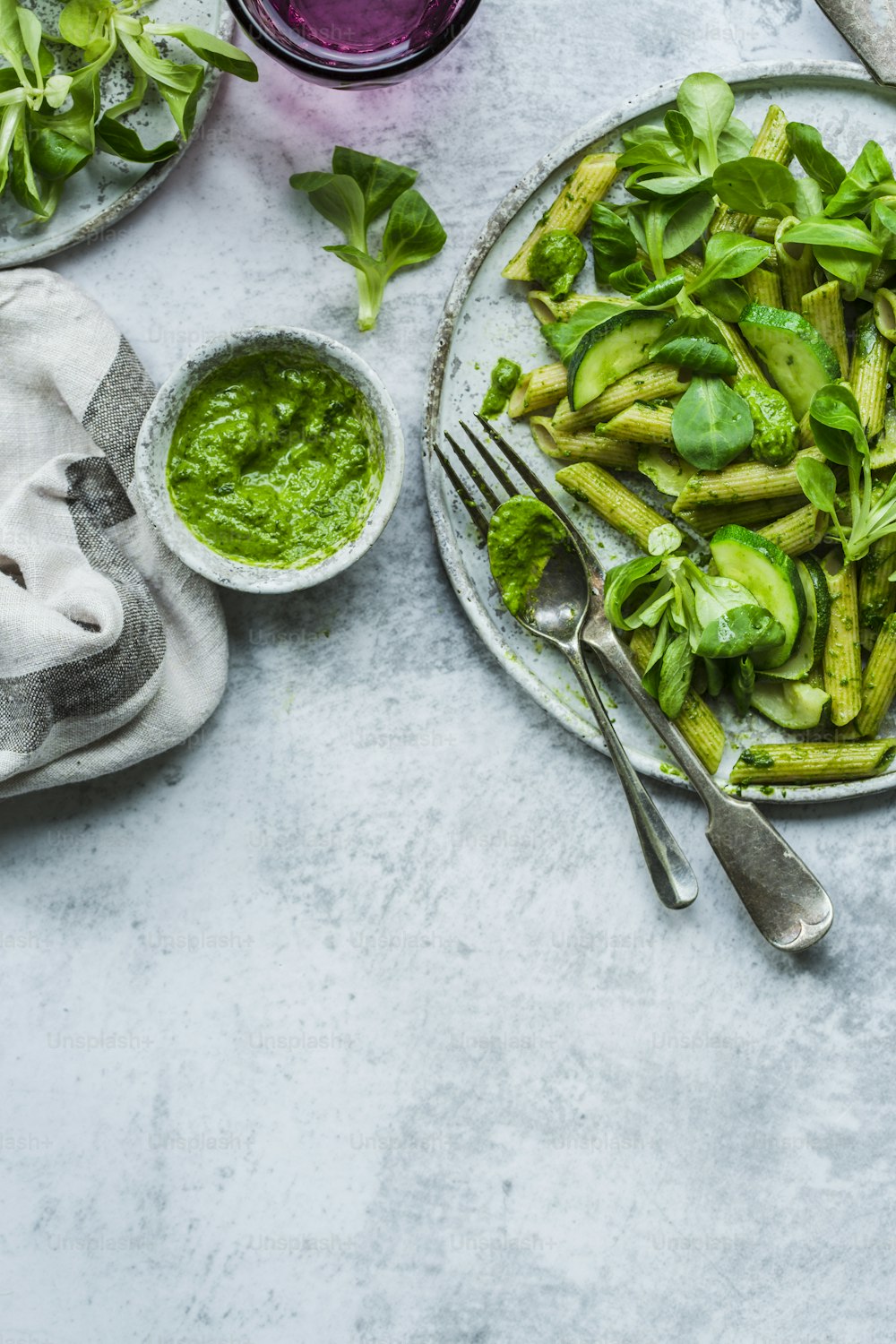 a plate of green vegetables and a bowl of pesto