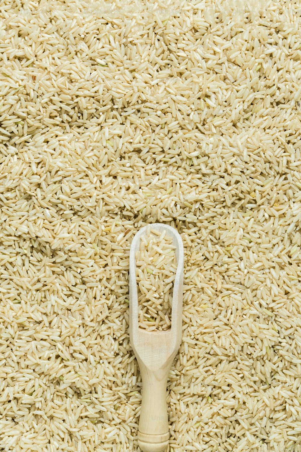 a wooden scoop of rice on top of a pile of rice