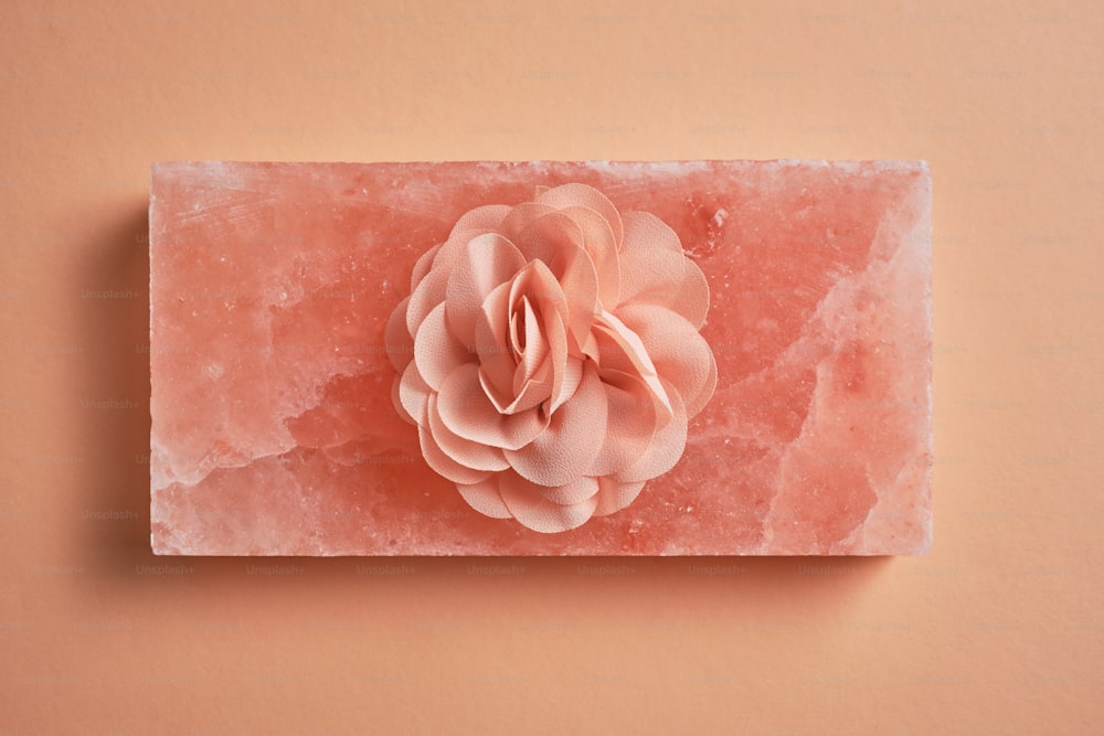a pink flower is placed on a piece of ice