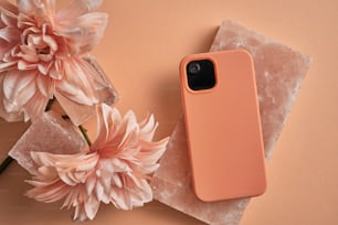 Eine rosafarbene iPhone-Hülle sitzt auf einem Tisch neben einer Blume