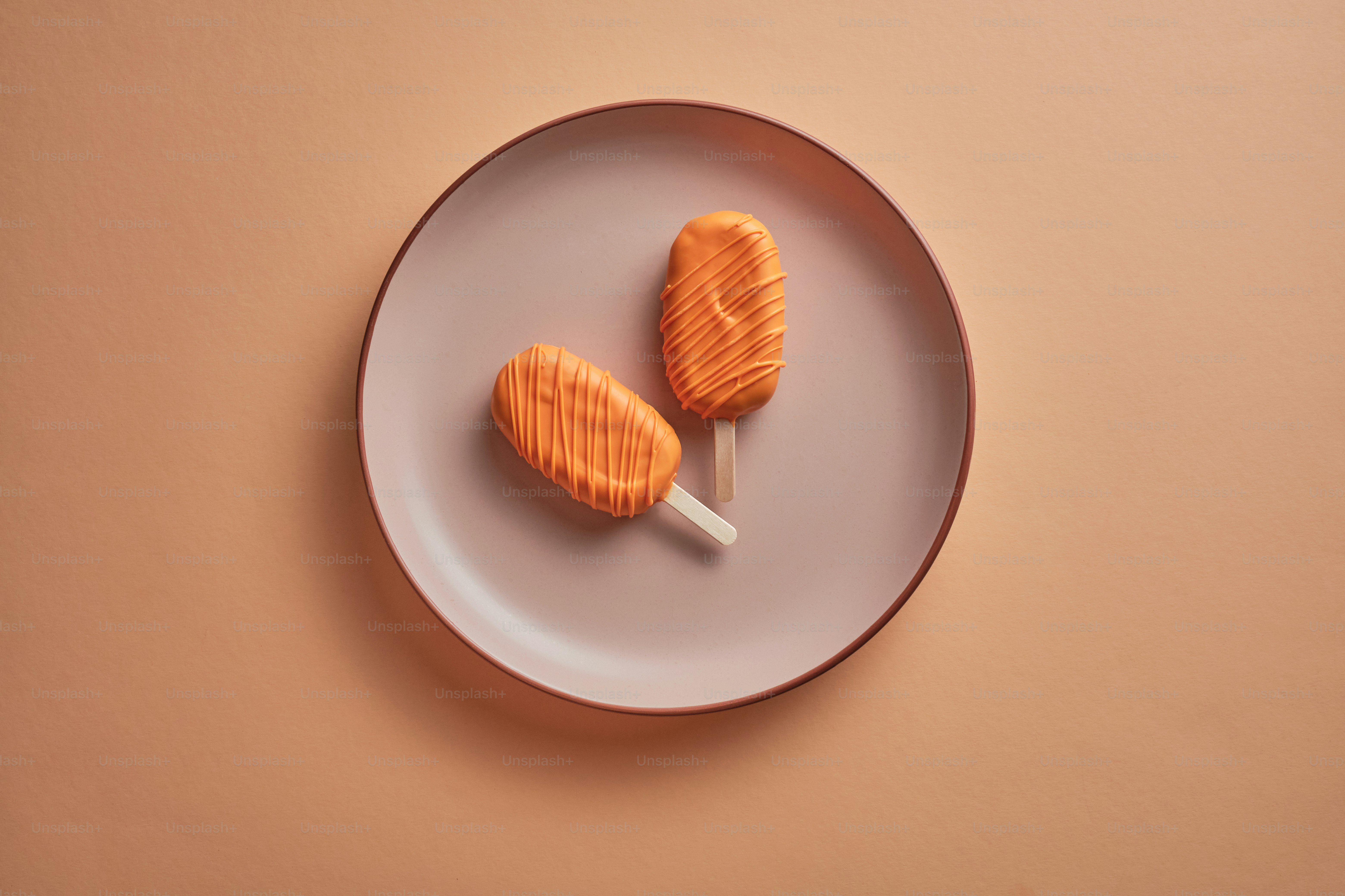 Orange popsicle on a peach fuzz colored background