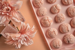un vassoio rosa di biscotti accanto a un fiore rosa