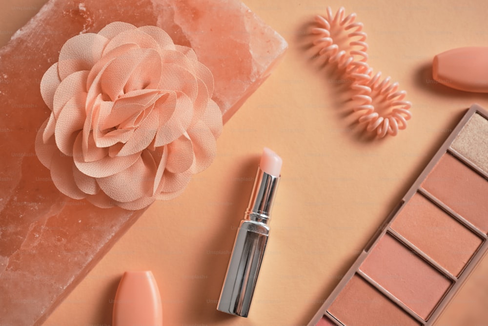 a close up of a lipstick and a flower on a table