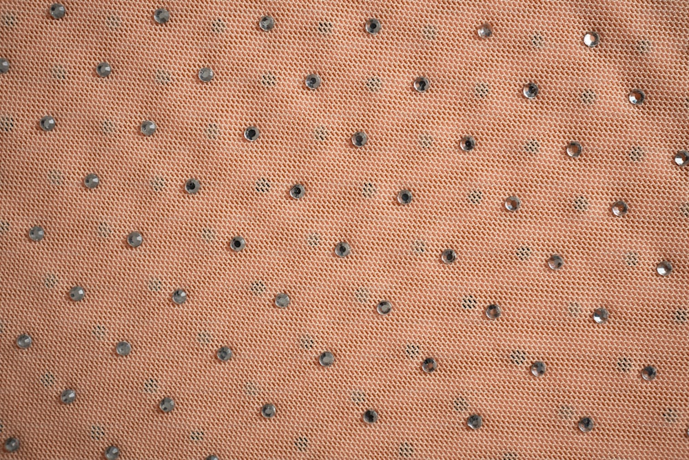 a close up of an orange fabric with silver dots