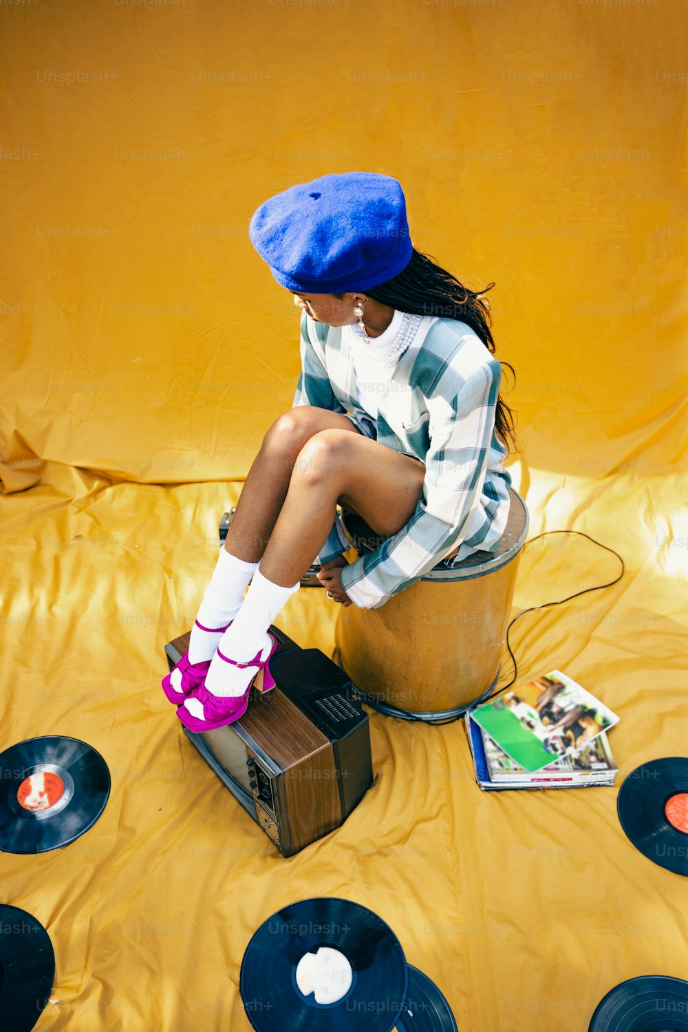a woman sitting on top of a bucket filled with vinyl records