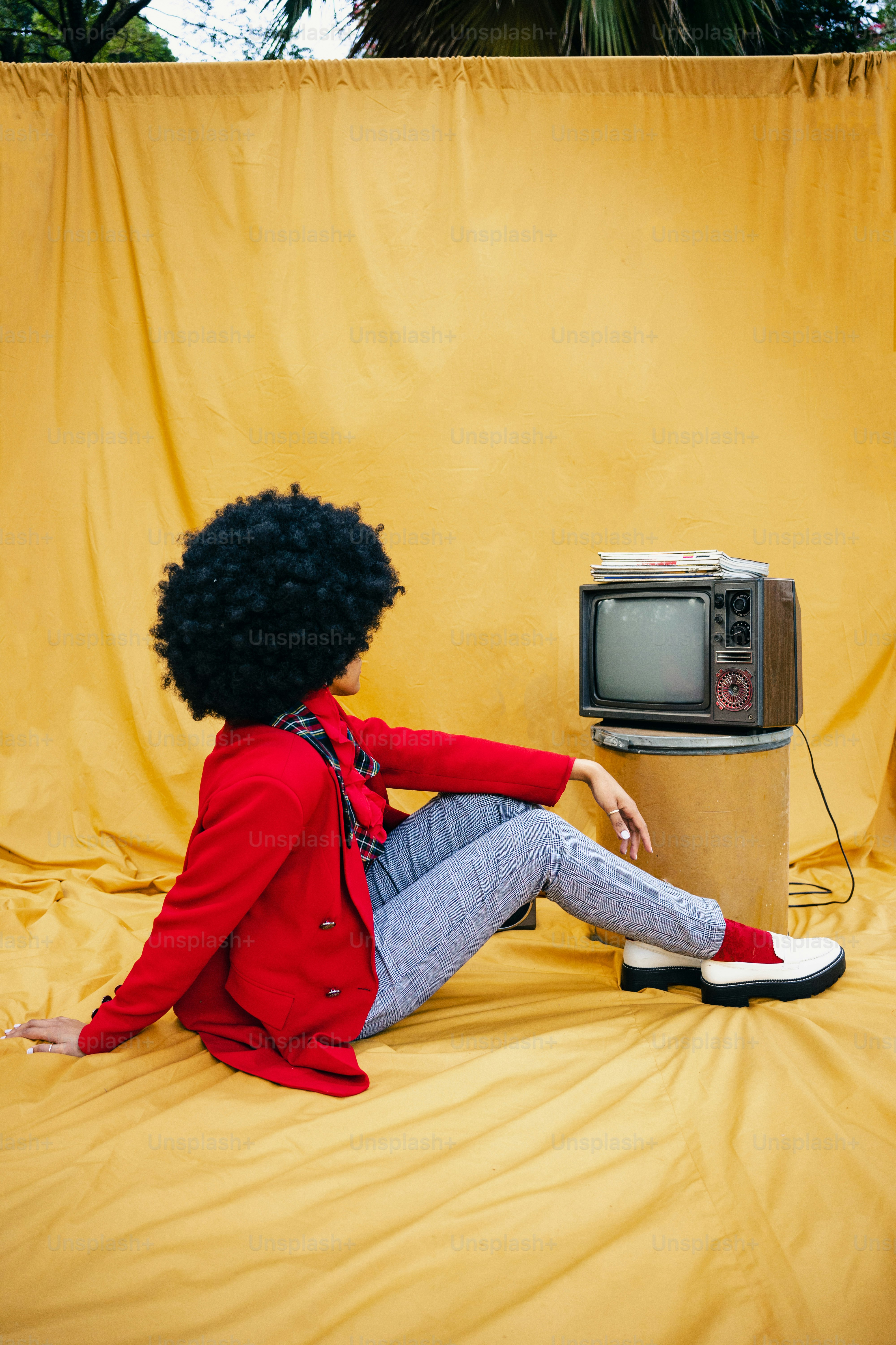 Une femme assise par terre à côté d’une télévision