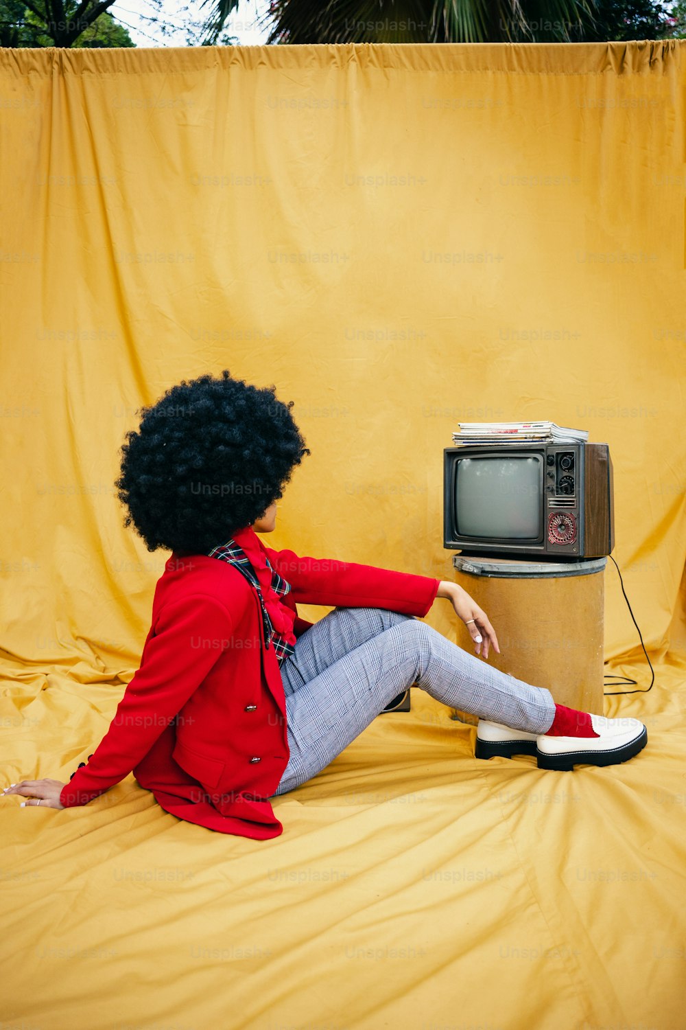 a woman sitting on the ground next to a tv