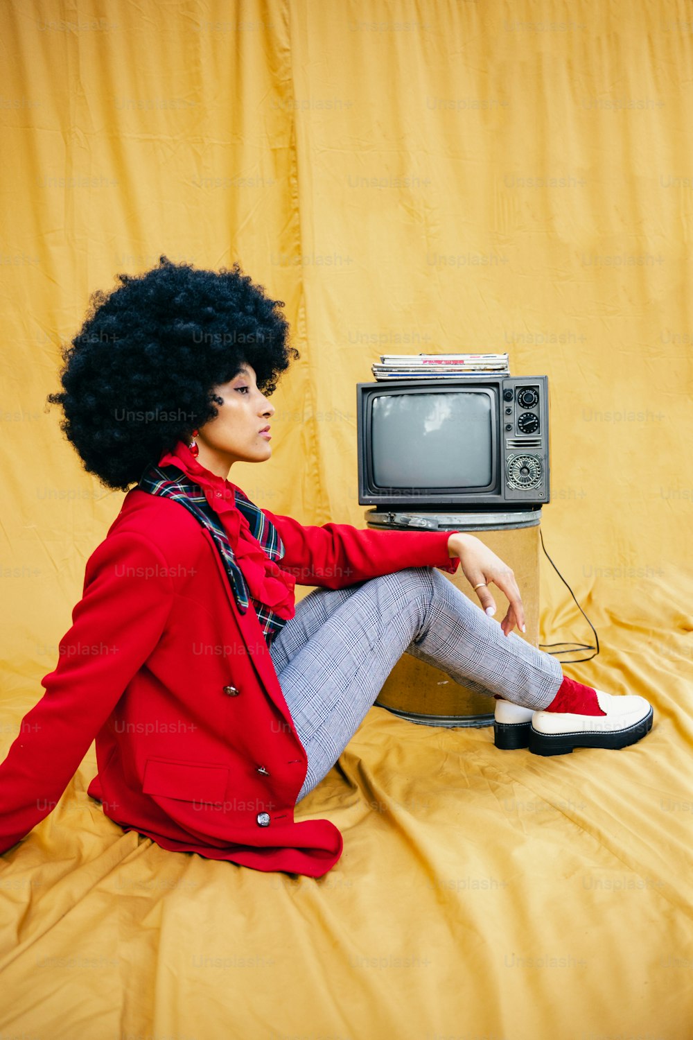 a woman sitting on top of a bed next to a tv