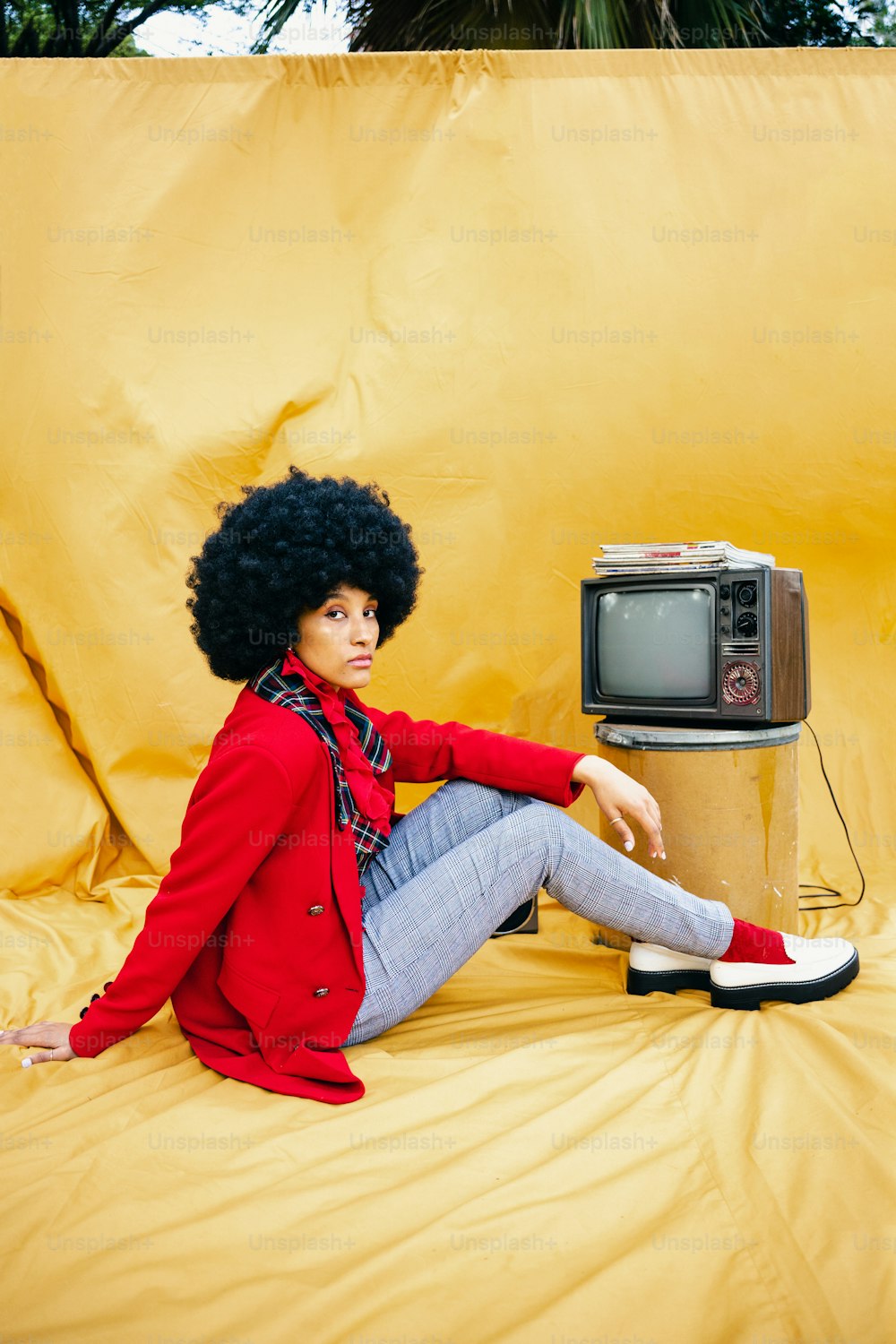 a woman in a red jacket sitting on a yellow background