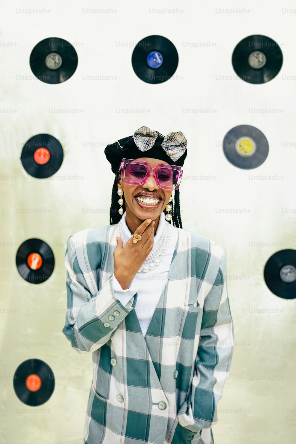 a woman wearing a hat and sunglasses standing in front of a record wall
