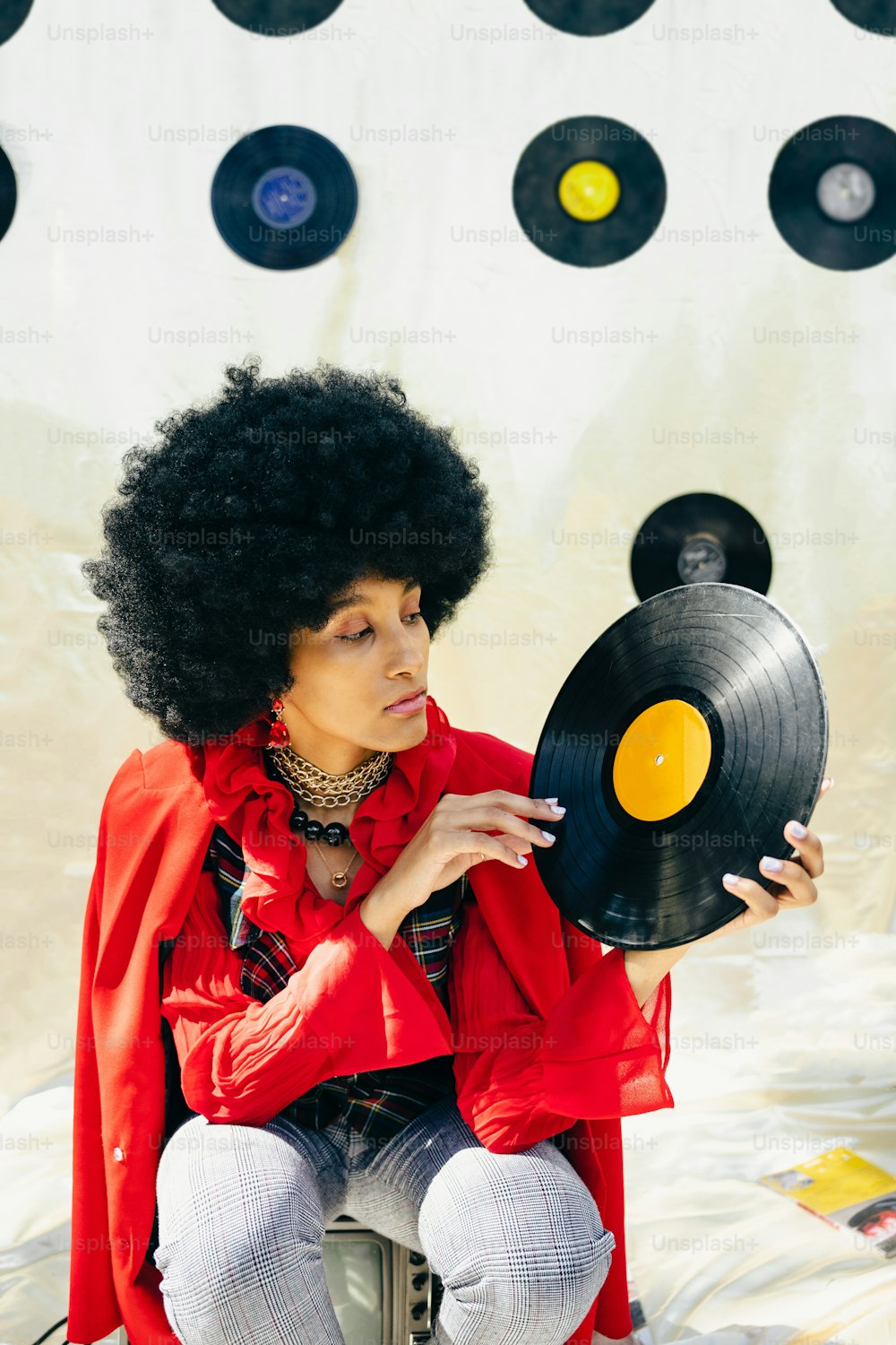 a woman sitting on a stool holding a record