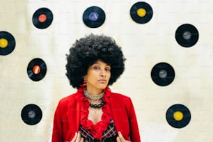 a woman with an afro standing in front of a record wall