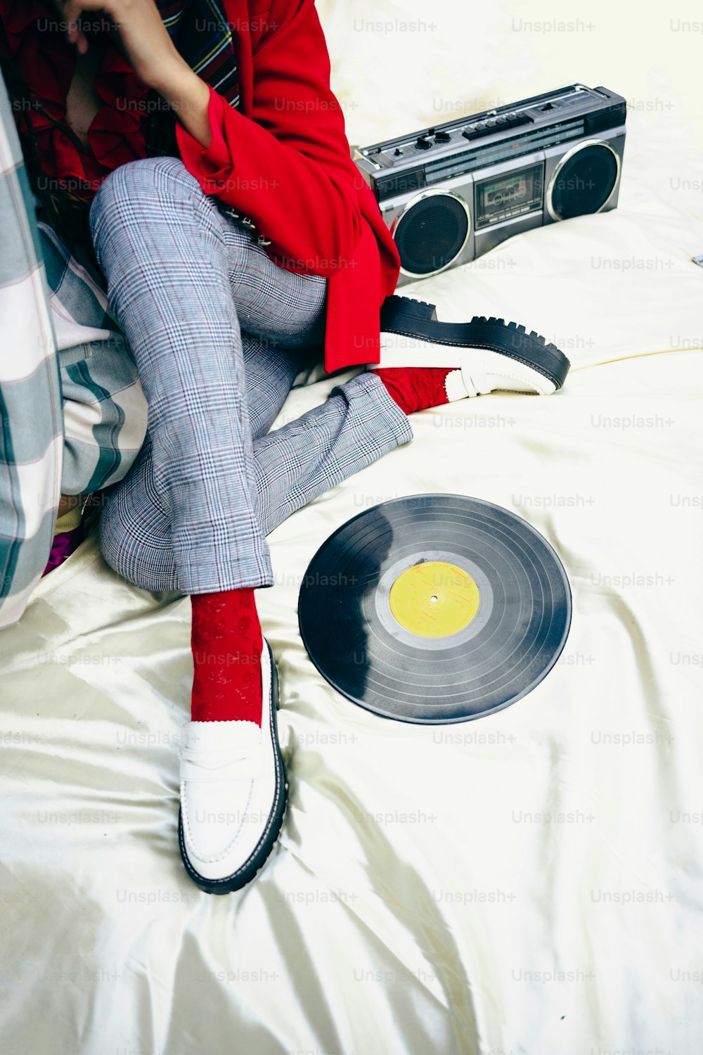 uma mulher sentada em uma cama ao lado de um toca-discos