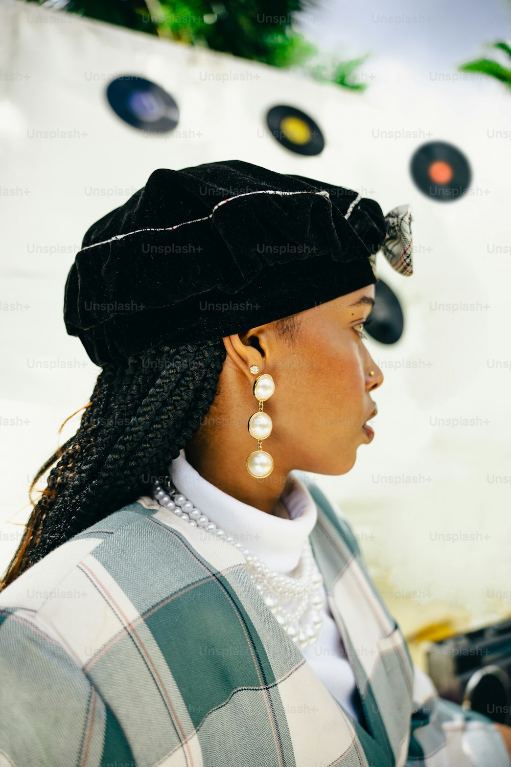 a woman wearing a black hat and pearls