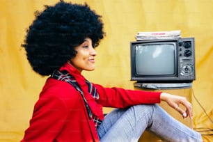 a woman with an afro sitting in front of a tv