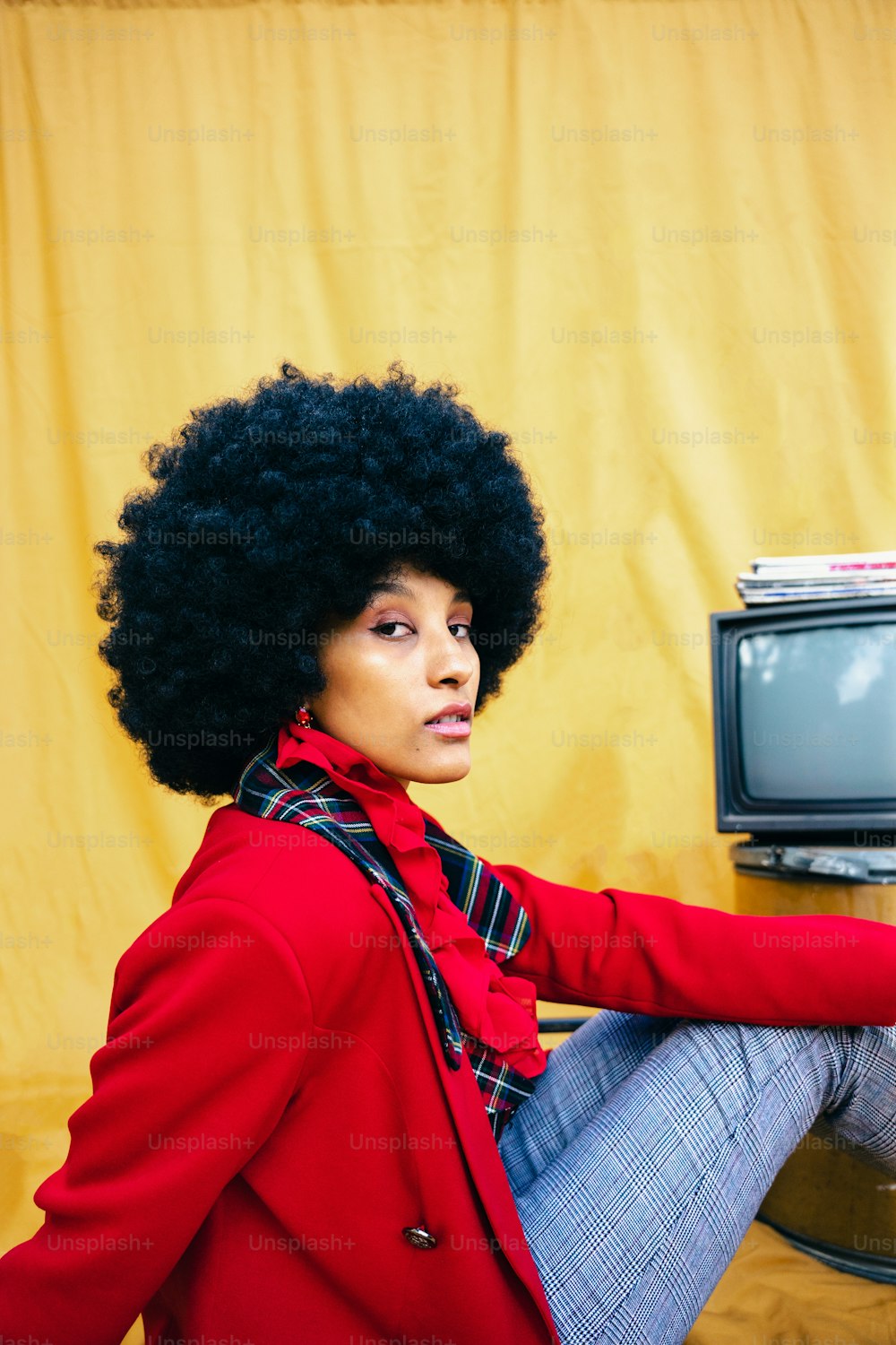 a woman with an afro sitting in front of a tv