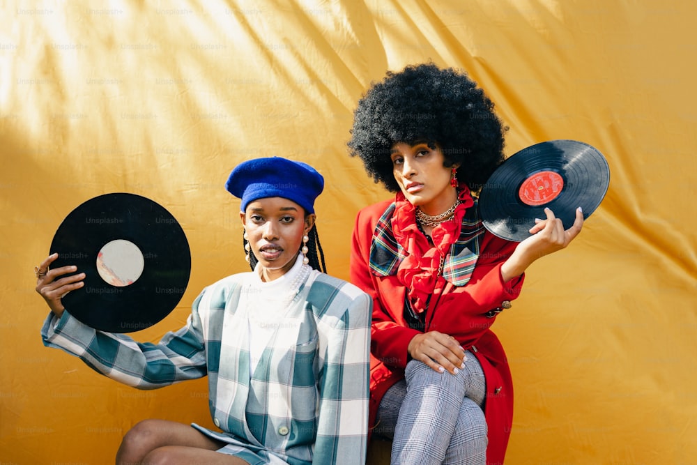 a couple of women sitting next to each other holding records