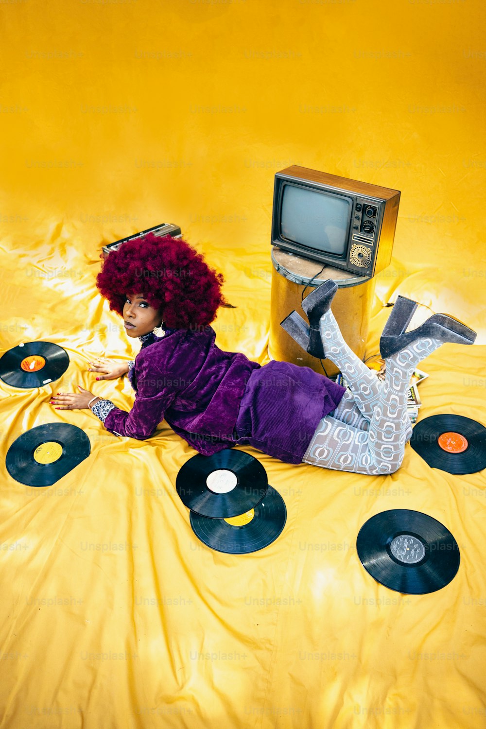 a woman laying on top of a bed covered in records