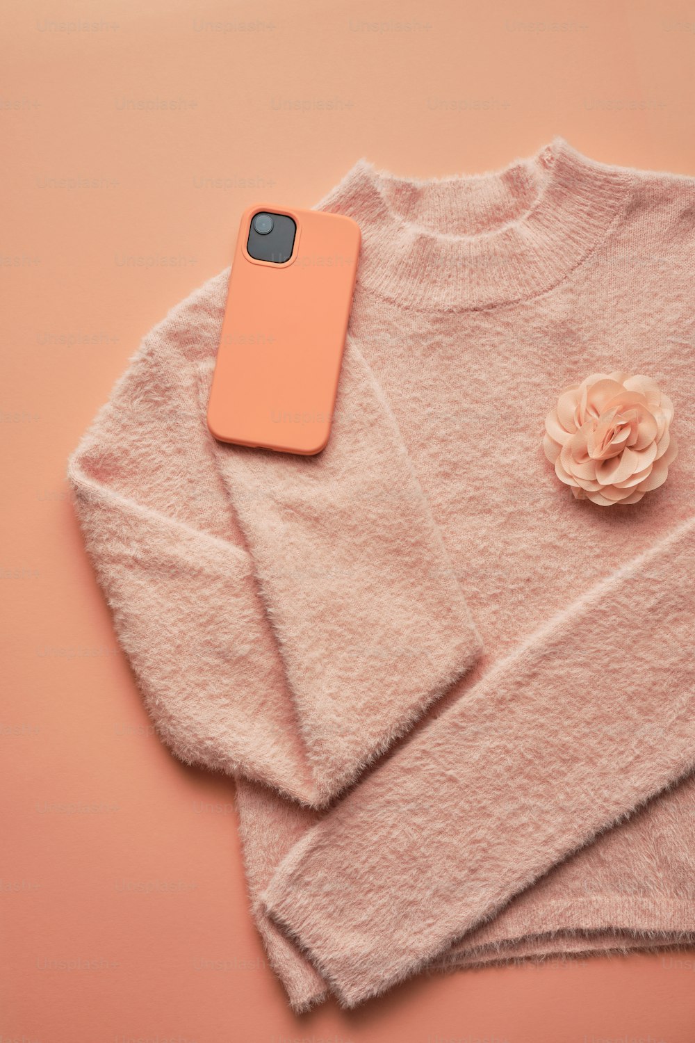 a cell phone laying on top of a pink sweater