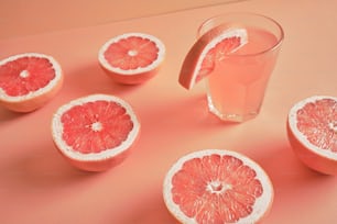 pompelmi e un bicchiere d'acqua su una superficie rosa