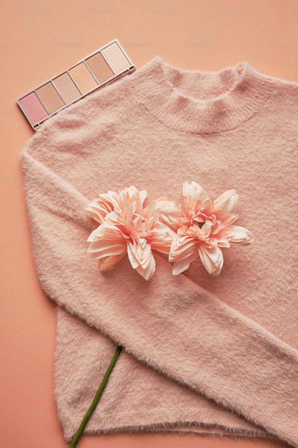 a pink sweater with flowers on top of it