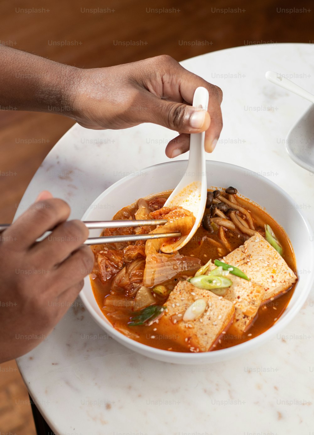 a person eating a bowl of soup with tofu