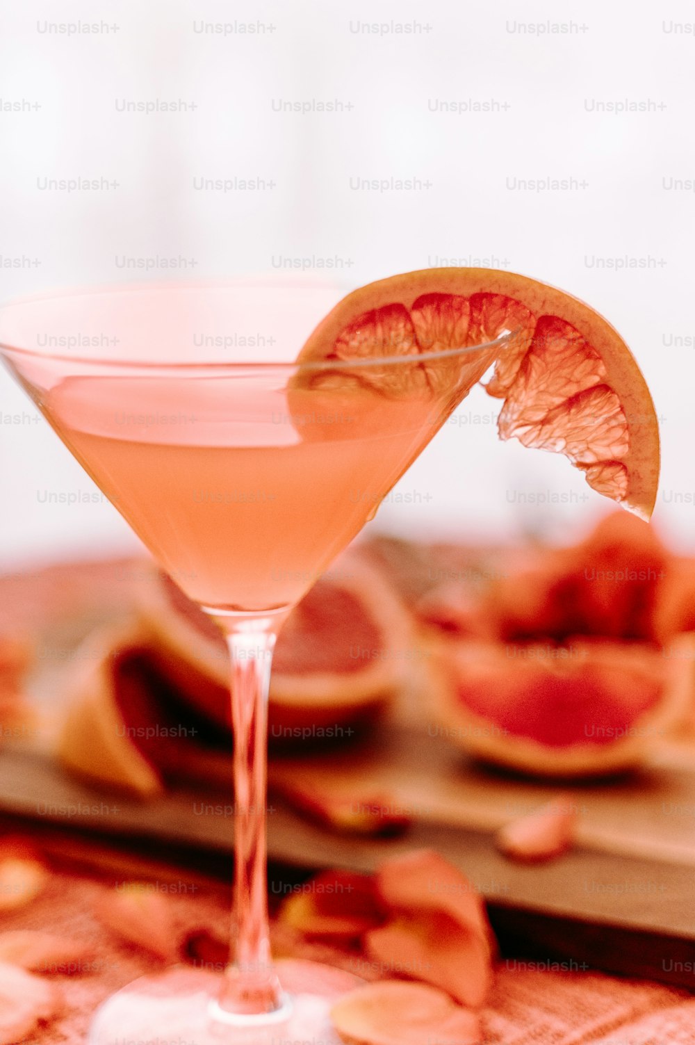 a pink cocktail garnished with an orange slice