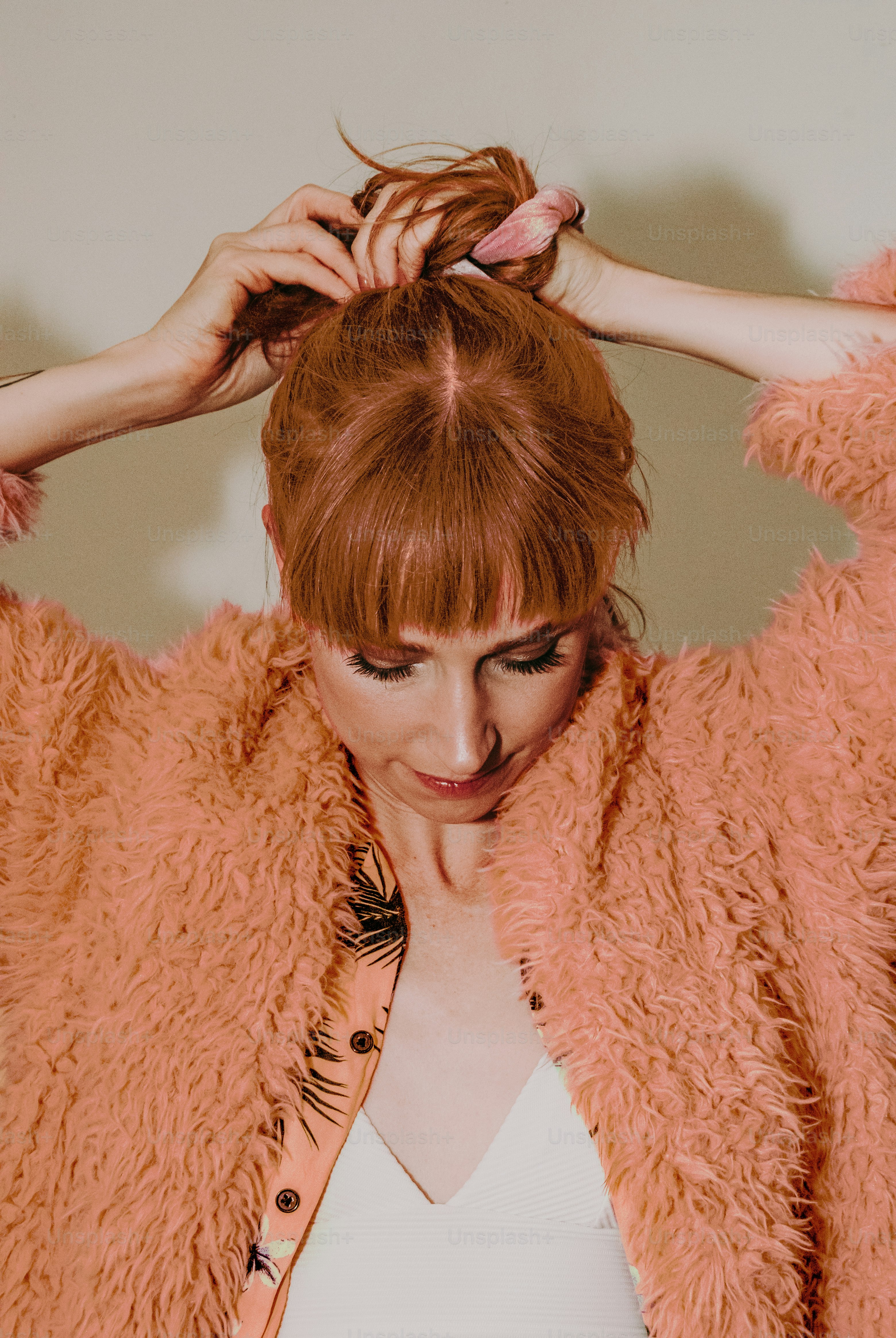 a woman with red hair is putting her hair in a bun