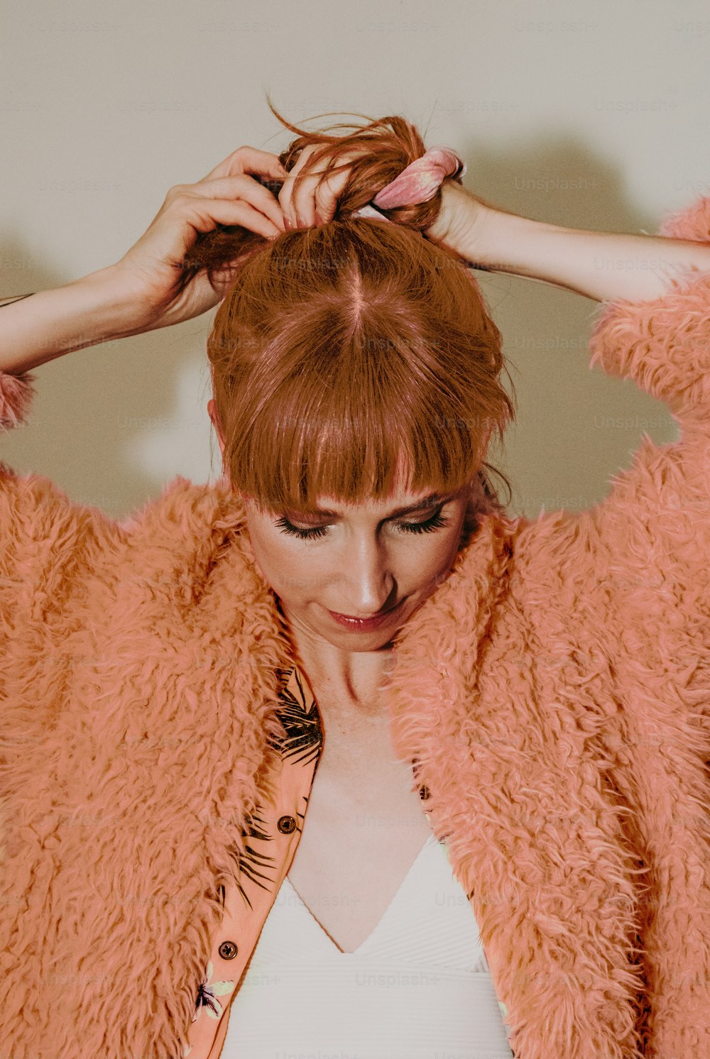 a woman with red hair is putting her hair in a bun