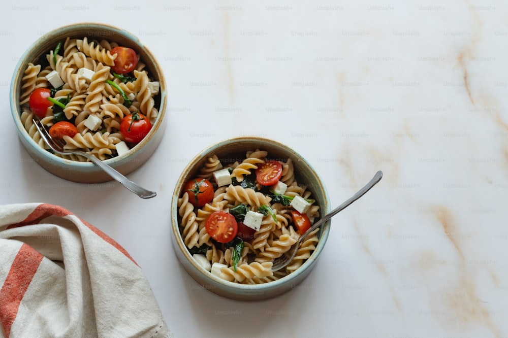 two bowls of pasta with tomatoes, onions, and cheese