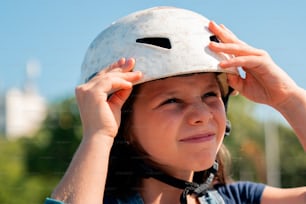 una joven con un casco blanco y sosteniéndose la cabeza