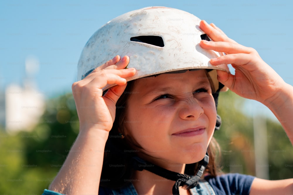a young girl wearing a white helmet and holding her head