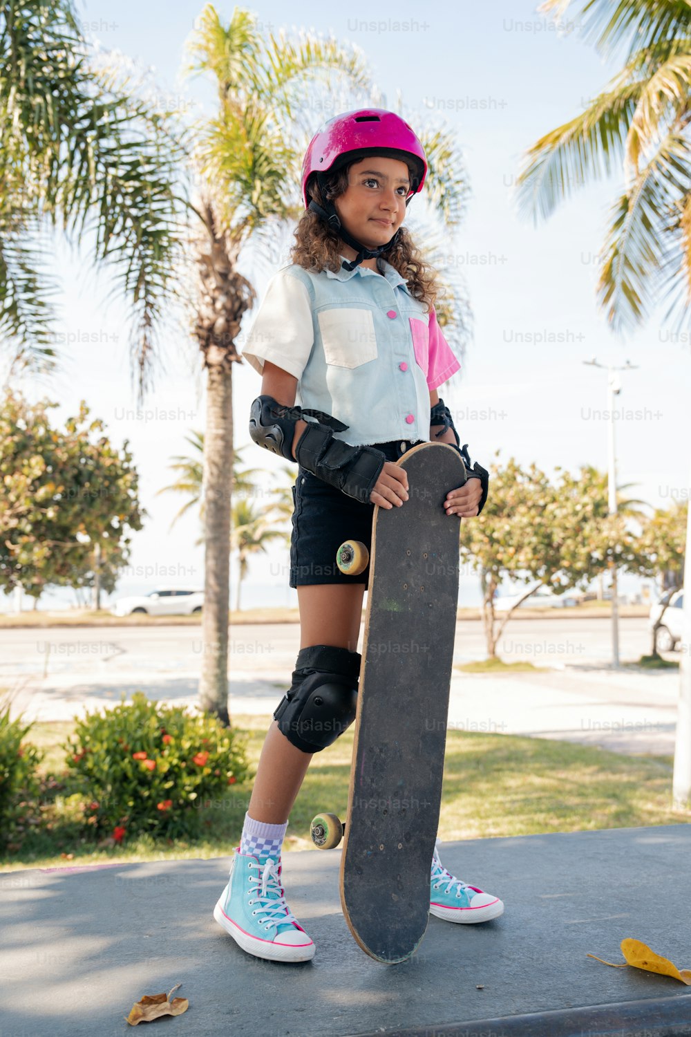 a young girl holding a skateboard on a sidewalk