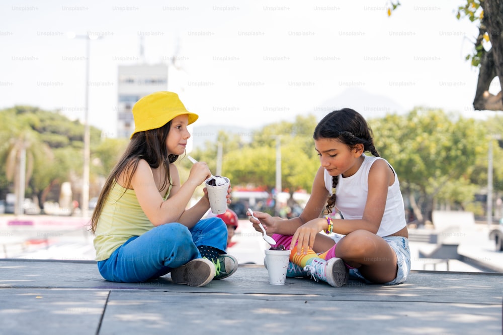 two young girls sitting on the ground eating food