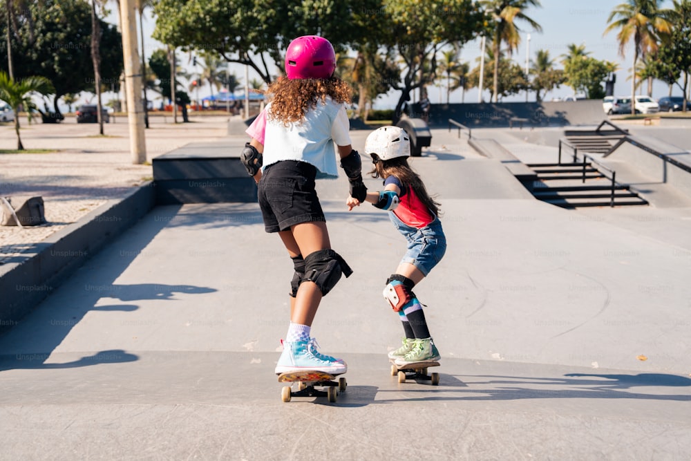 uma mulher ensinando uma menina a andar de skate