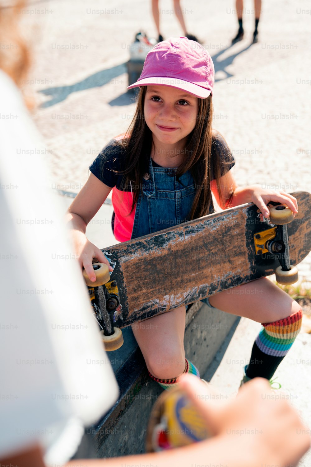 a young girl sitting on a bench holding a skateboard