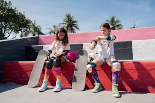 two girls sitting on a bench with skateboards