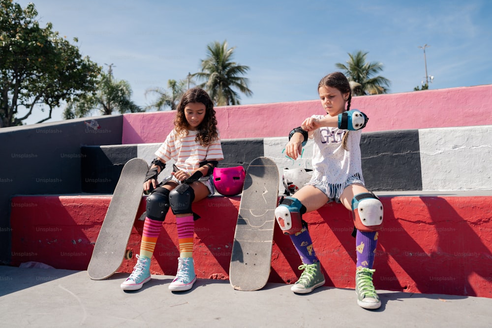 two girls sitting on a bench with skateboards