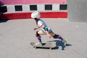 una giovane ragazza che cavalca uno skateboard su una superficie di cemento