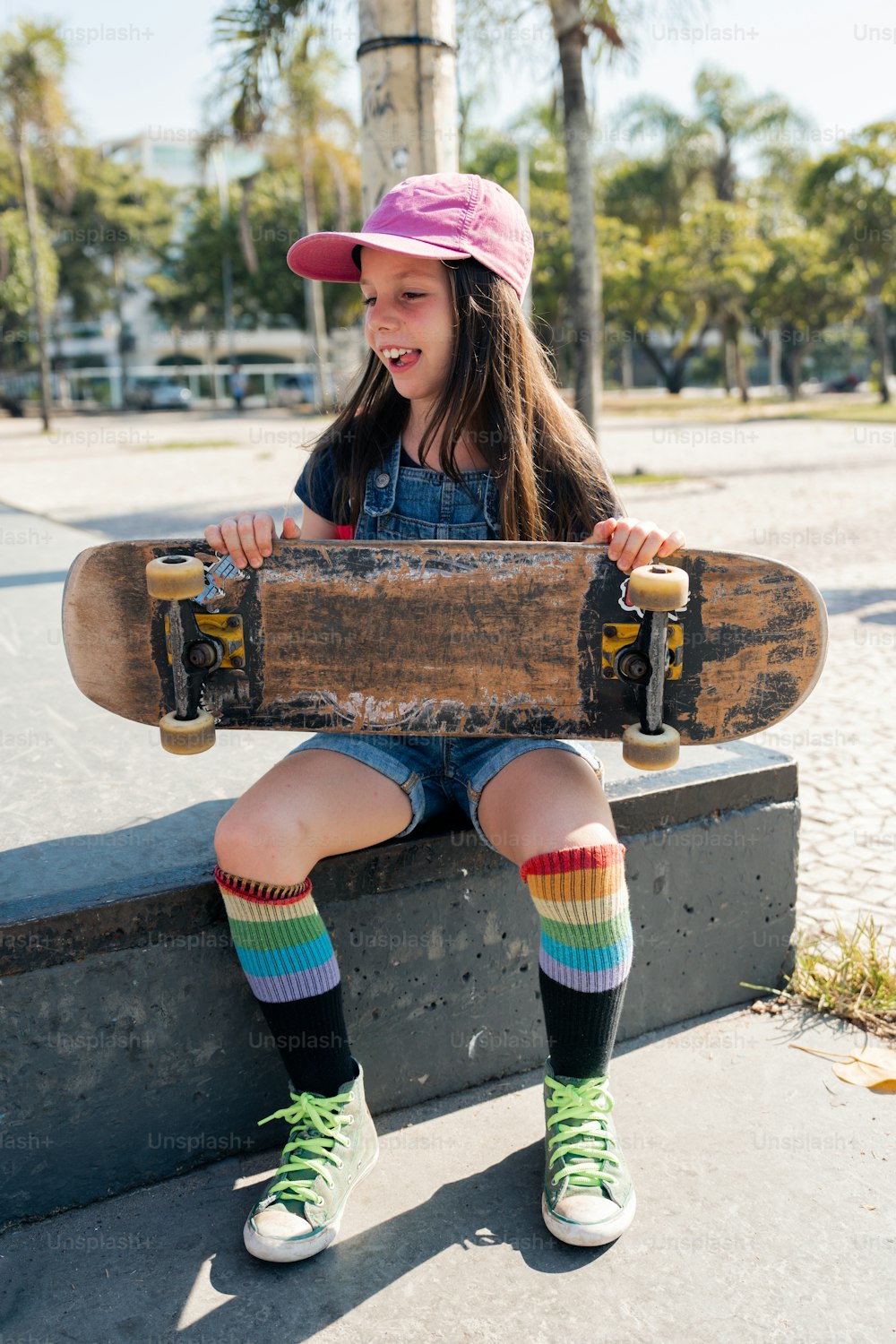 a young girl sitting on a bench holding a skateboard