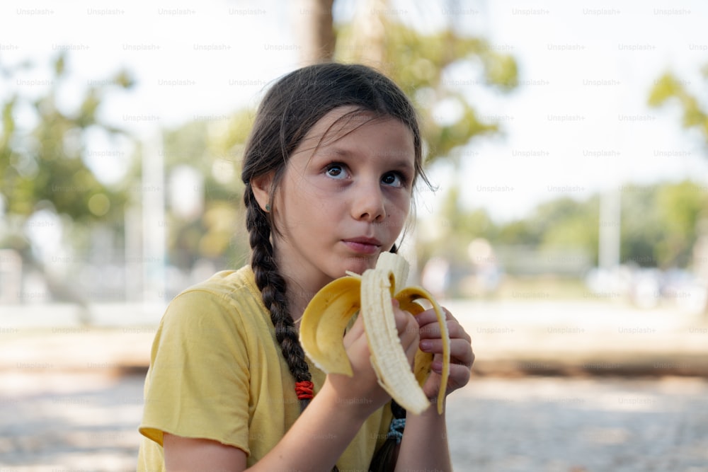 a little girl holding a banana in her hand