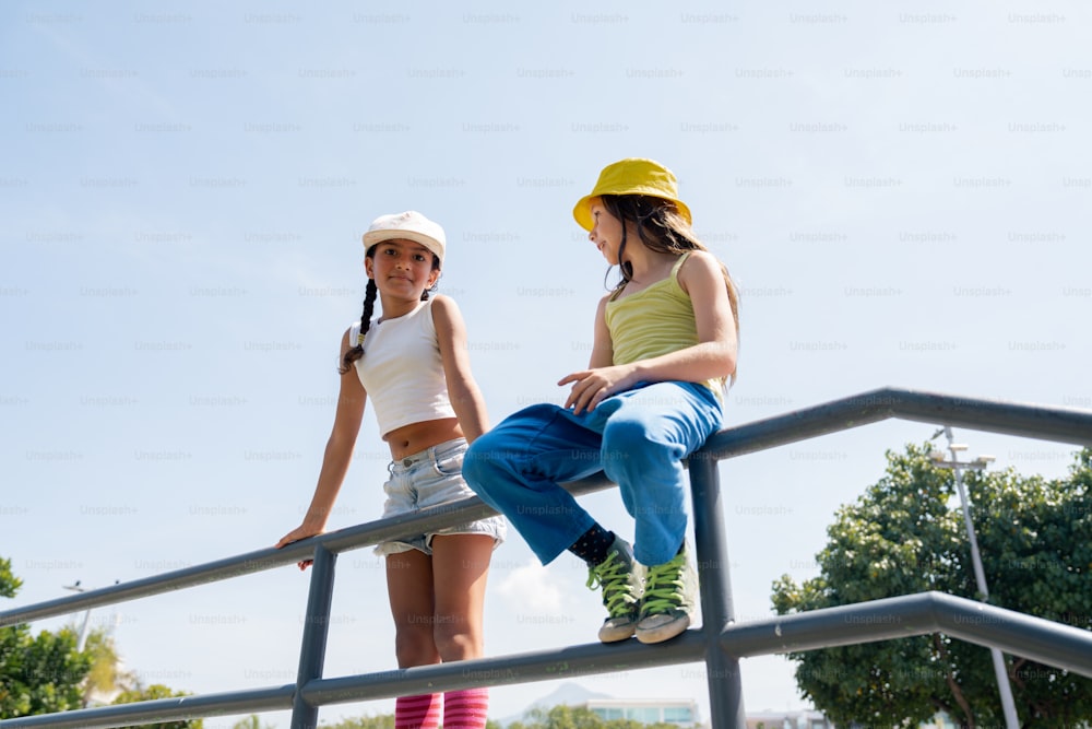 two young women sitting on a metal rail