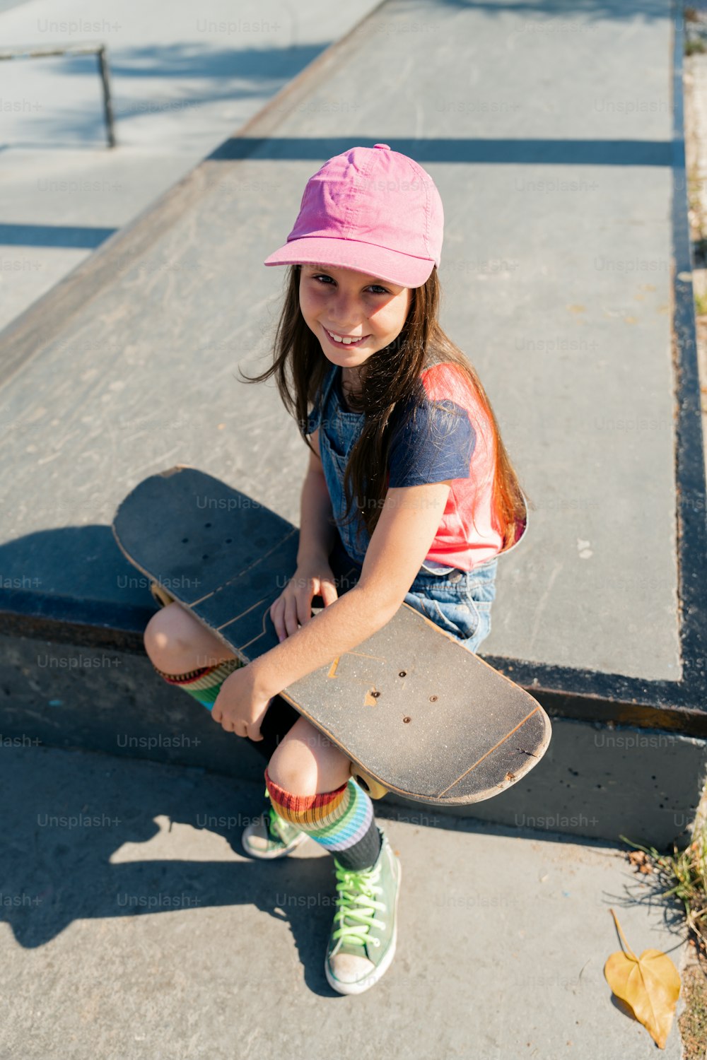 a young girl sitting on the ground with a skateboard
