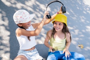 two young girls sitting on the ground with headphones on