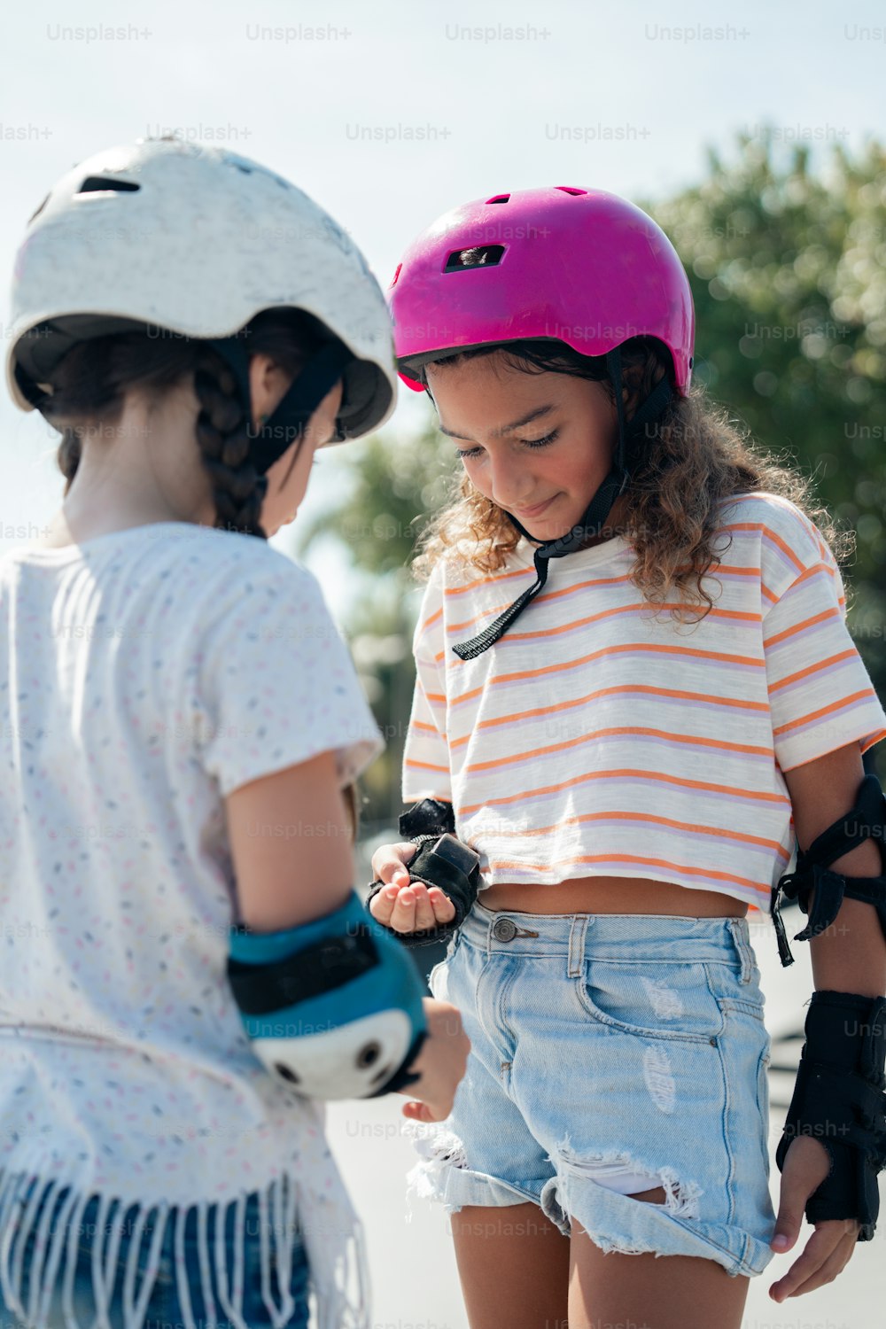 two young girls wearing helmets and knee pads