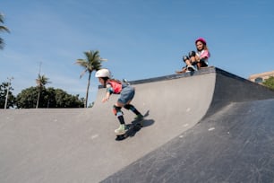 a couple of kids riding on top of a skateboard ramp