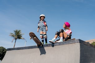 a couple of kids sitting on top of a skateboard ramp